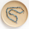 The knotted aquamarine rose necklace styled on a tan plate to show the adjustable lobster clasp closure