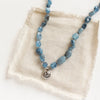 The knotted aquamarine rose necklace styled on tan linen