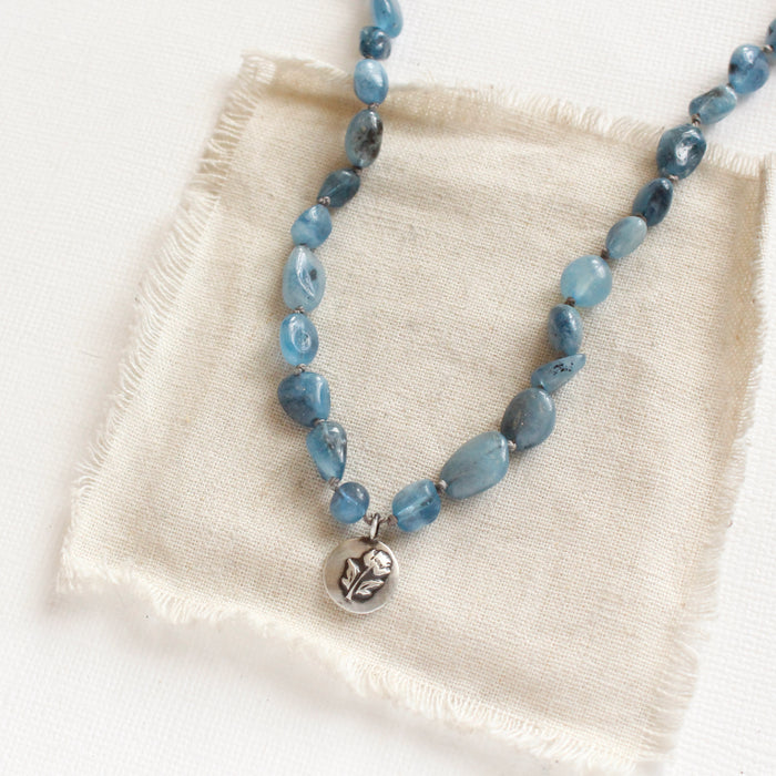 The knotted aquamarine rose necklace styled on tan linen