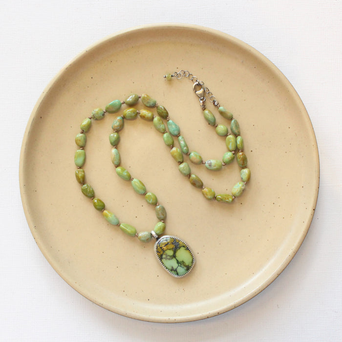 The knotted elisa and hubei turquoise necklace styled on a tan plate to show the adjustable lobster clasp closure