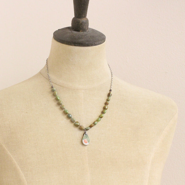 A mannequin wearing the knotted elisa turquoise, peridot, and peach blossom necklace