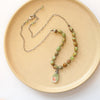 The knotted elisa turquoise, peridot, and peach blossom necklace styled on a tan plate to show the adjustable lobster clasp closure