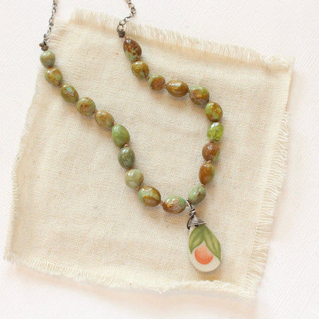 The knotted elisa turquoise & peridot peach blossom vintage plate necklace styled on tan linen