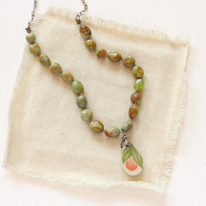 The knotted elisa turquoise & peridot peach blossom vintage plate necklace styled on tan linen
