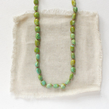 The knotted campitos turquoise necklace styled on tan linen