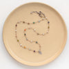 The knotted kaleidoscope leaf necklace styled on a tan plate to show the adjustable lobster clasp closure