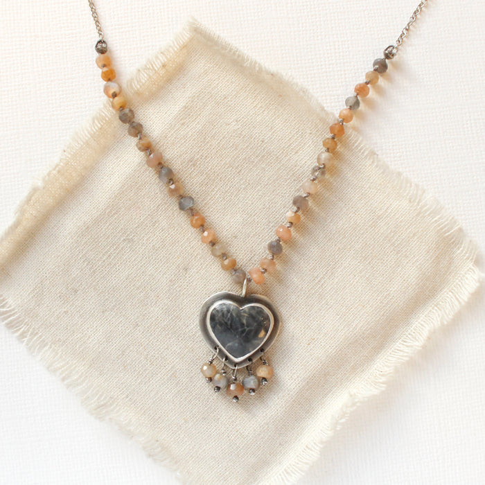 The knotted moonstone heart necklace styled on tan linen