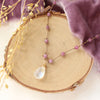 The knotted moonstone and ruby necklace styled on wood with purple velvet and dried grass
