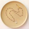 The knotted moonstone and ruby necklace styled on a plate to show the adjustable lobster clasp closure