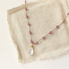The knotted ruby and moonstone necklace styled on tan linen