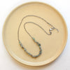 The knotted opal necklace styled on a tan plate to show the adjustable lobster clasp closure