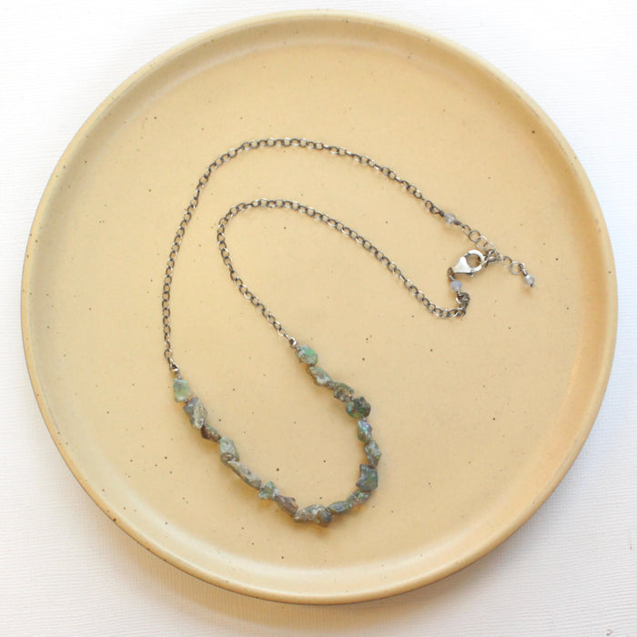 The knotted opal necklace styled on a tan plate to show the adjustable lobster clasp closure
