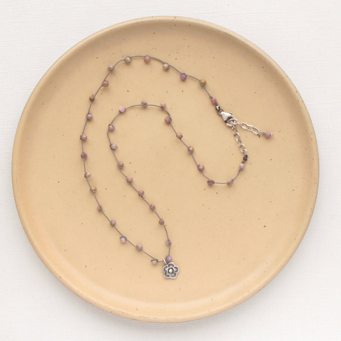 The knotted phosphosiderite mini cactus flower necklace styled on a tan plate to show the adjustable lobster clasp closure