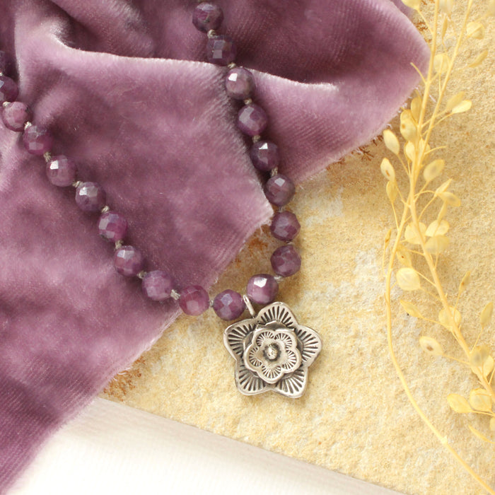 A close shot of the flower pendant on the knotted purple ruby layered cactus flower necklace