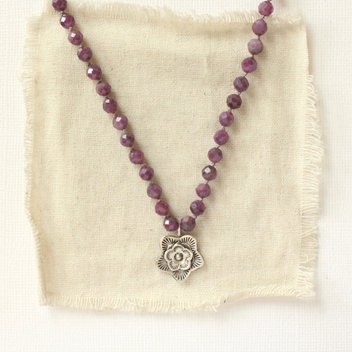 The knotted purple ruby layered cactus flower necklace styled on tan linen