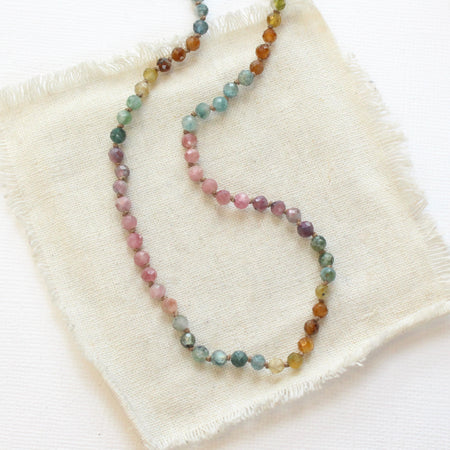 The knotted tourmaline necklace styled on tan linen