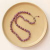 The knotted ruby nugget necklace styled on a plate to show the adjustable lobster clasp closure