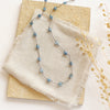 The knotted aquamarine necklace styled on a tan rock with linen and dried grass
