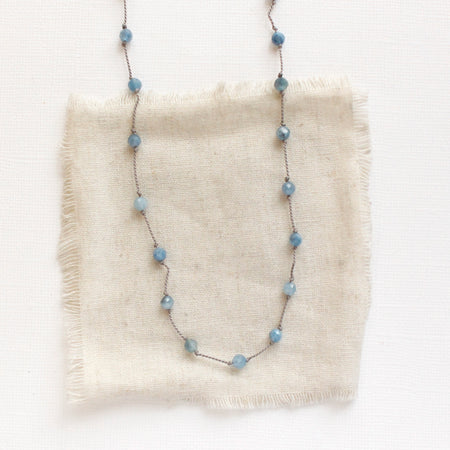 The knotted aquamarine necklace styled on tan linen