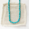 The knotted sleeping beauty turquoise necklace styled on tan linen