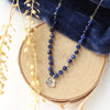 The knotted sodalite mini cactus flower necklace styled on wood with blue velvet and dried grass