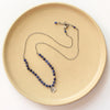 The knotted sodalite mini cactus flower necklace styled on a tan plate to show the adjustable lobster clasp closure