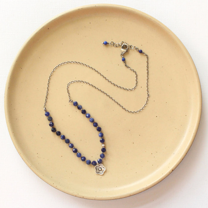 The knotted sodalite mini cactus flower necklace styled on a tan plate to show the adjustable lobster clasp closure