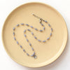 The knotted tanzanite mini cactus flower necklace styled on a tan plate to show the adjustable lobster clasp closure