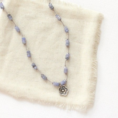 The knotted tanzanite mini cactus flower necklace styled on tan linen
