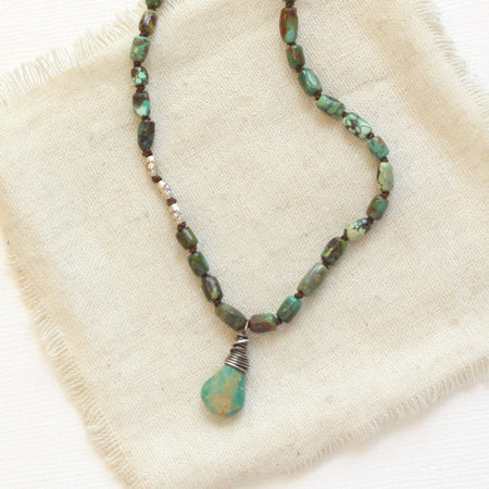 The knotted turquoise necklace styled on tan linen
