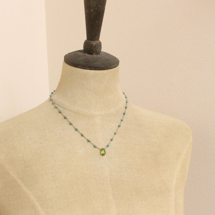 A mannequin wearing the knotted turquoise and peridot drop necklace