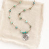 The knotted turquoise soar necklace styled on tan linen