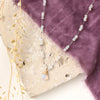 The knotted opal necklace styled on a tan rock with purple velvet and dried grass