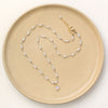 The knotted opal necklace styled on a tan plate to show the adjustable lobster clasp closure