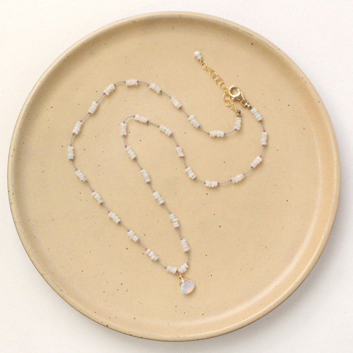 The knotted opal necklace styled on a tan plate to show the adjustable lobster clasp closure