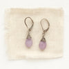 The light purple kunzite drop earrings styled on tan linen