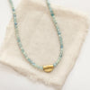 The beaded kyanite mythos necklace styled on tan linen