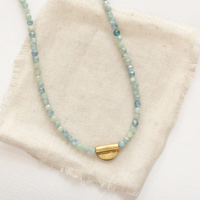 The beaded kyanite mythos necklace styled on tan linen
