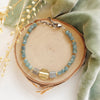 The mythos bracelet styled on wood with green velvet and dried grass