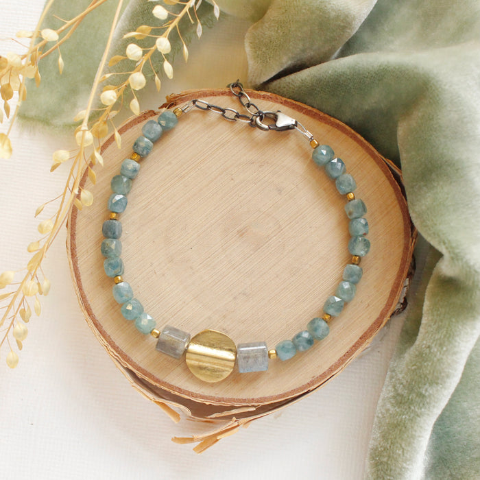 The mythos bracelet styled on wood with green velvet and dried grass