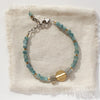 The kyanite and labradorite mixed metal mythos bracelet is styled on tan linen