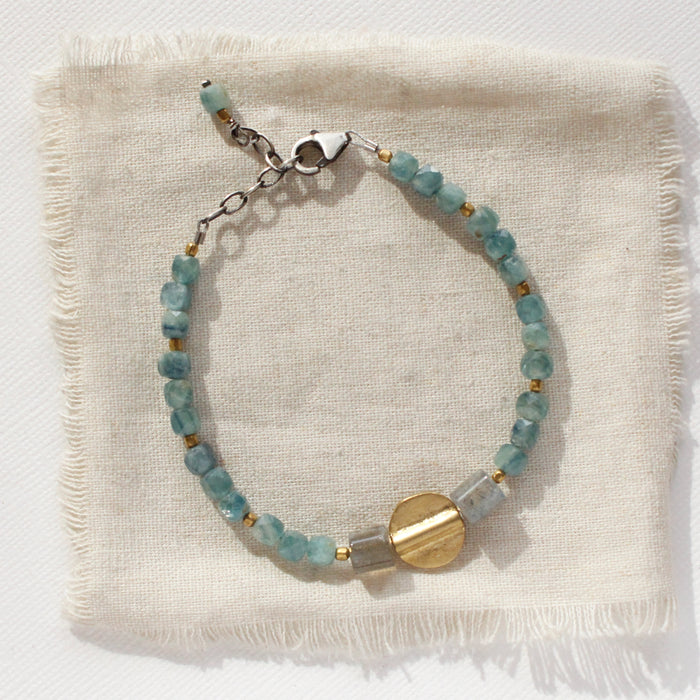 The kyanite and labradorite mixed metal mythos bracelet is styled on tan linen
