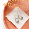 The labradorite la cloche earrings styled on an orange plate with linen and dried grass