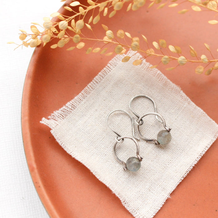 The labradorite la cloche earrings styled on an orange plate with linen and dried grass