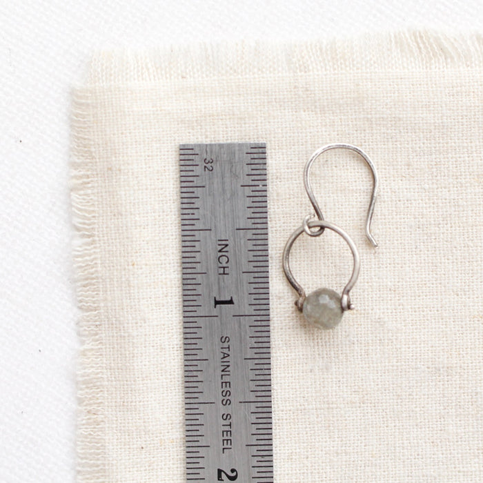 A labradorite la cloche earring next to a ruler for size reference