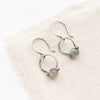 The labradorite la cloche earrings styled on tan linen