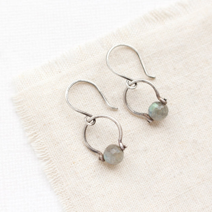 The labradorite la cloche earrings styled on tan linen