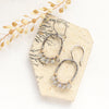 The labradorite wrapped mixed metal hoop earrings styled on a tan rock with dried grass