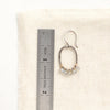 A labradorite wrapped mixed metal hoop earring next to a ruler for size reference