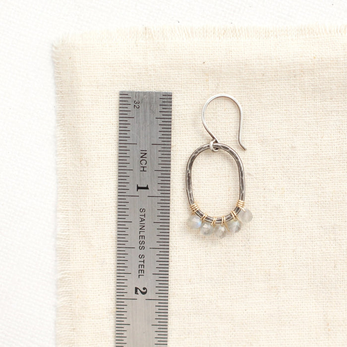 A labradorite wrapped mixed metal hoop earring next to a ruler for size reference